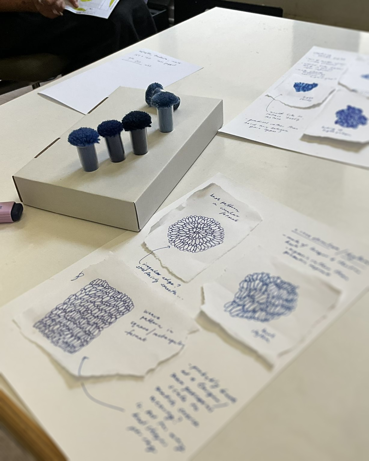 Design sketches and wool colour samples laid out on the studio table